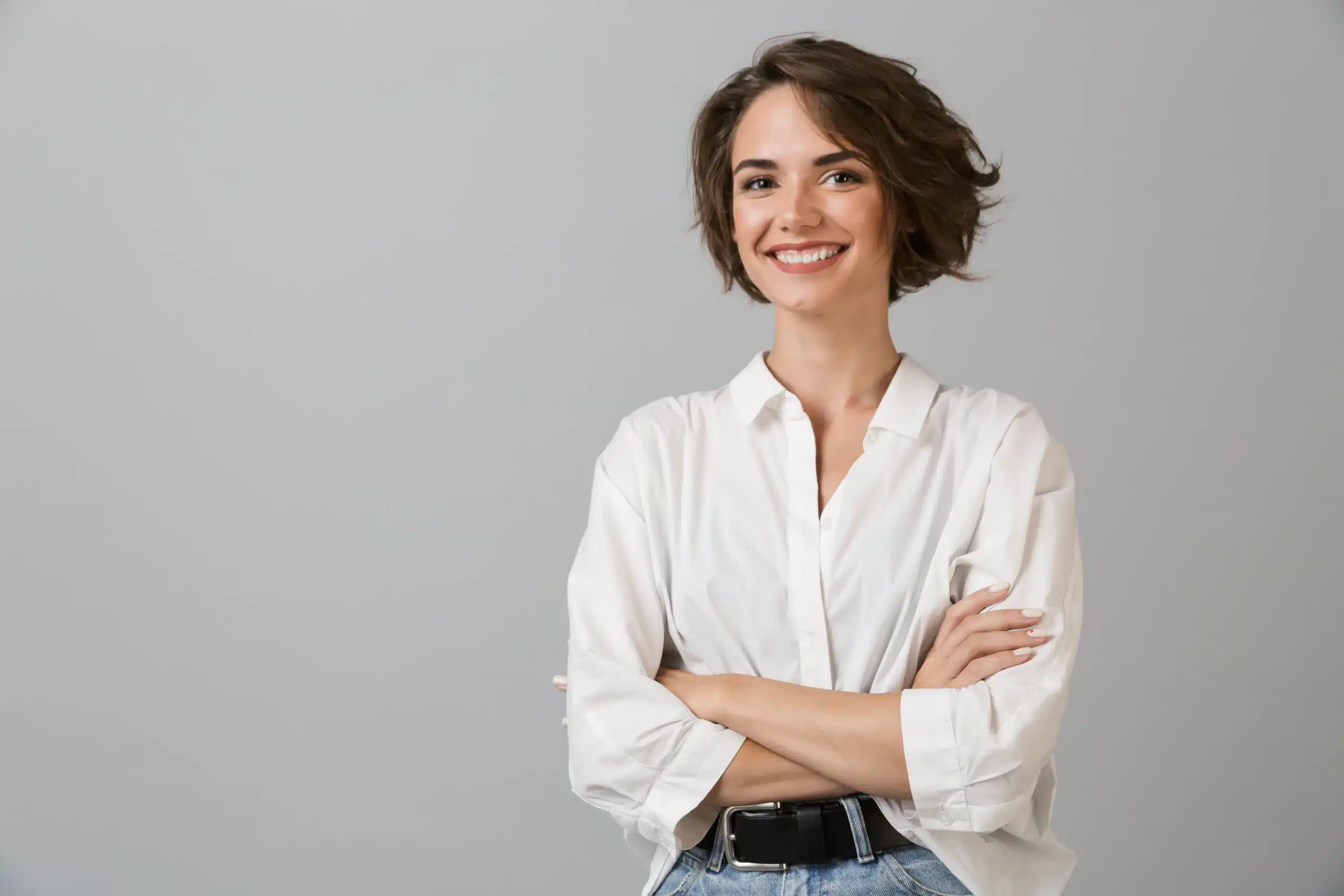 Smiling woman with short hair in a white shirt, arms crossed