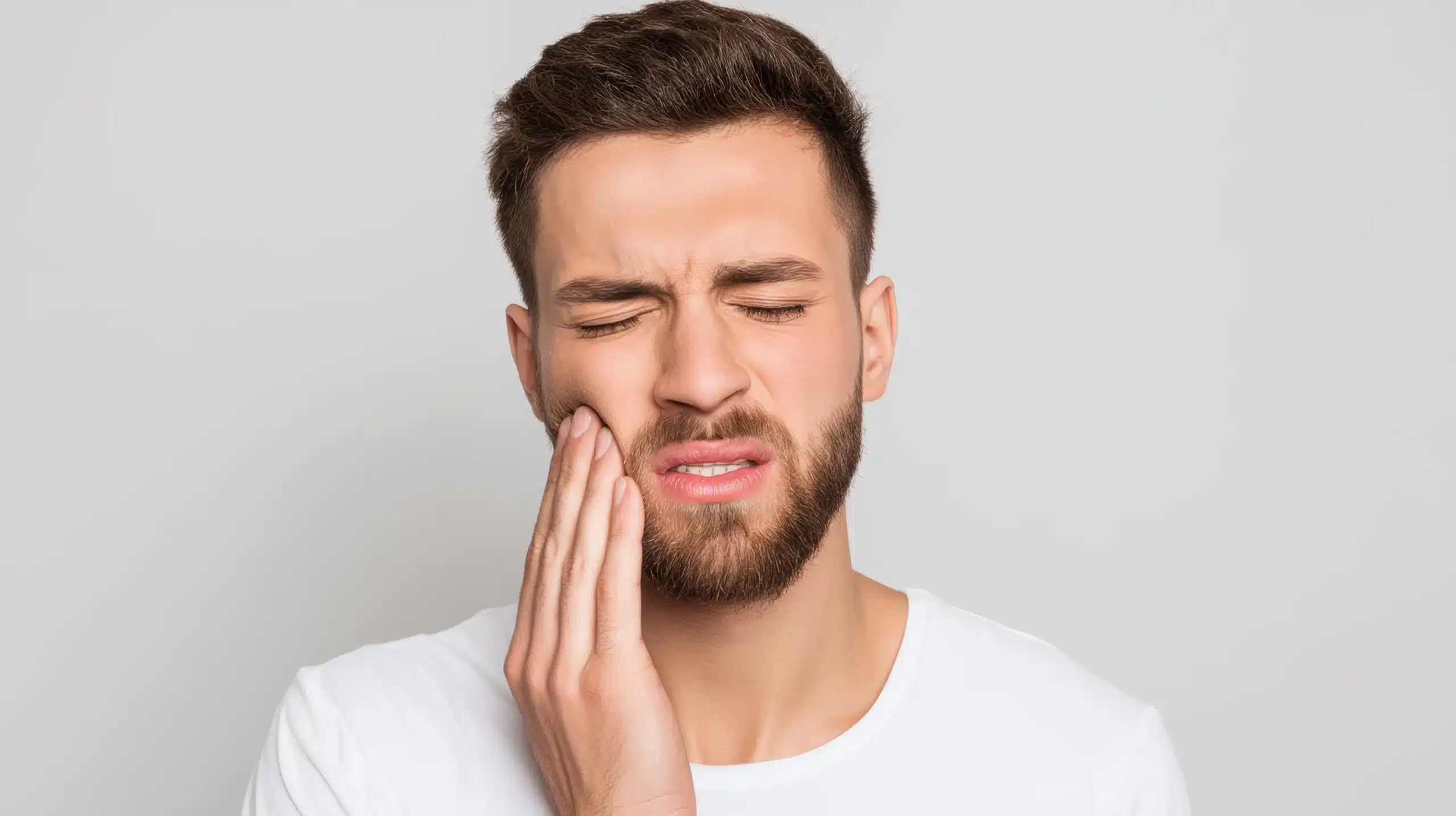 Man holding his cheek in pain from a toothache